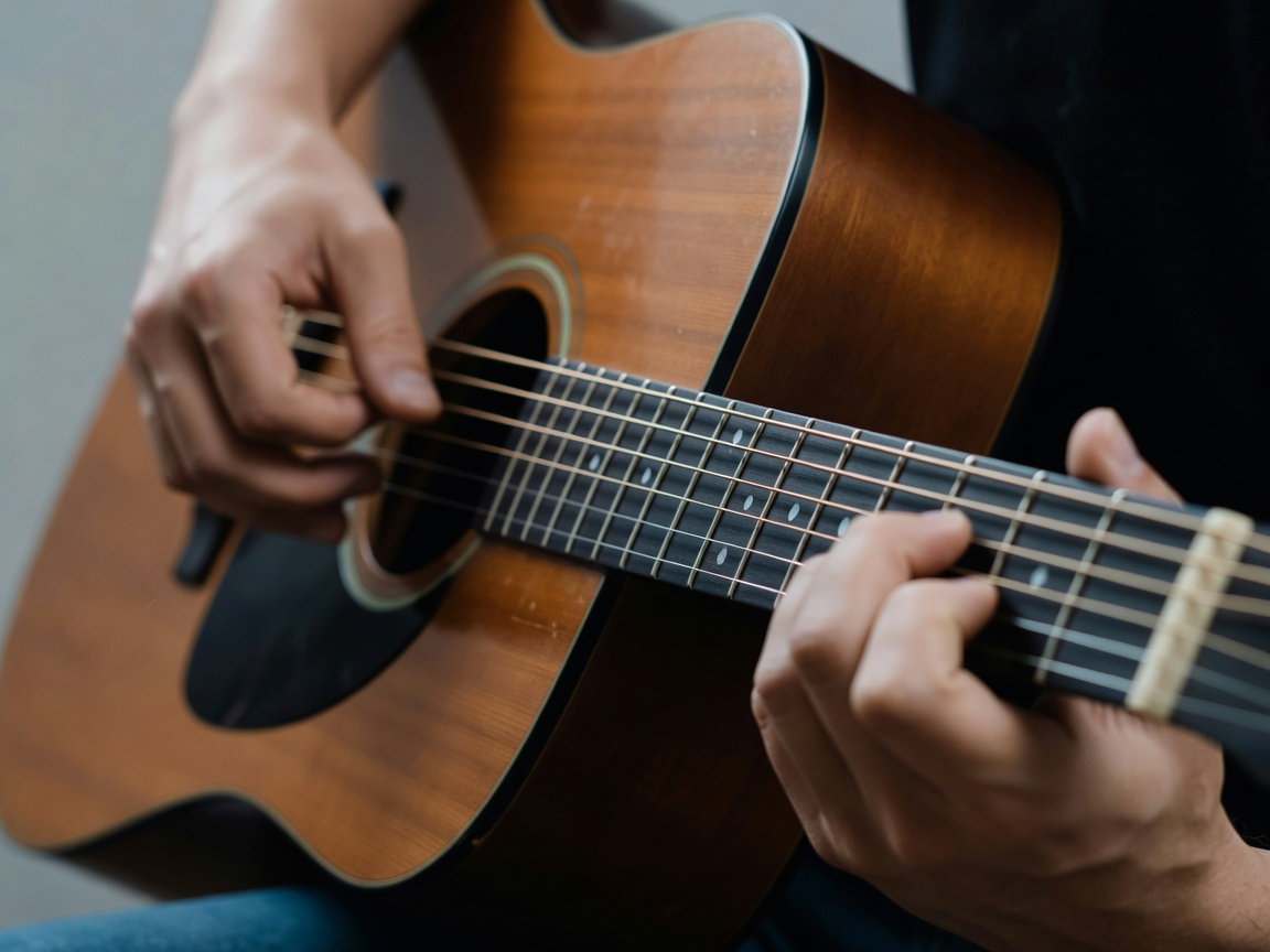 Detalle de una guitarra acústica y manos preparando un acorde en el diapasón